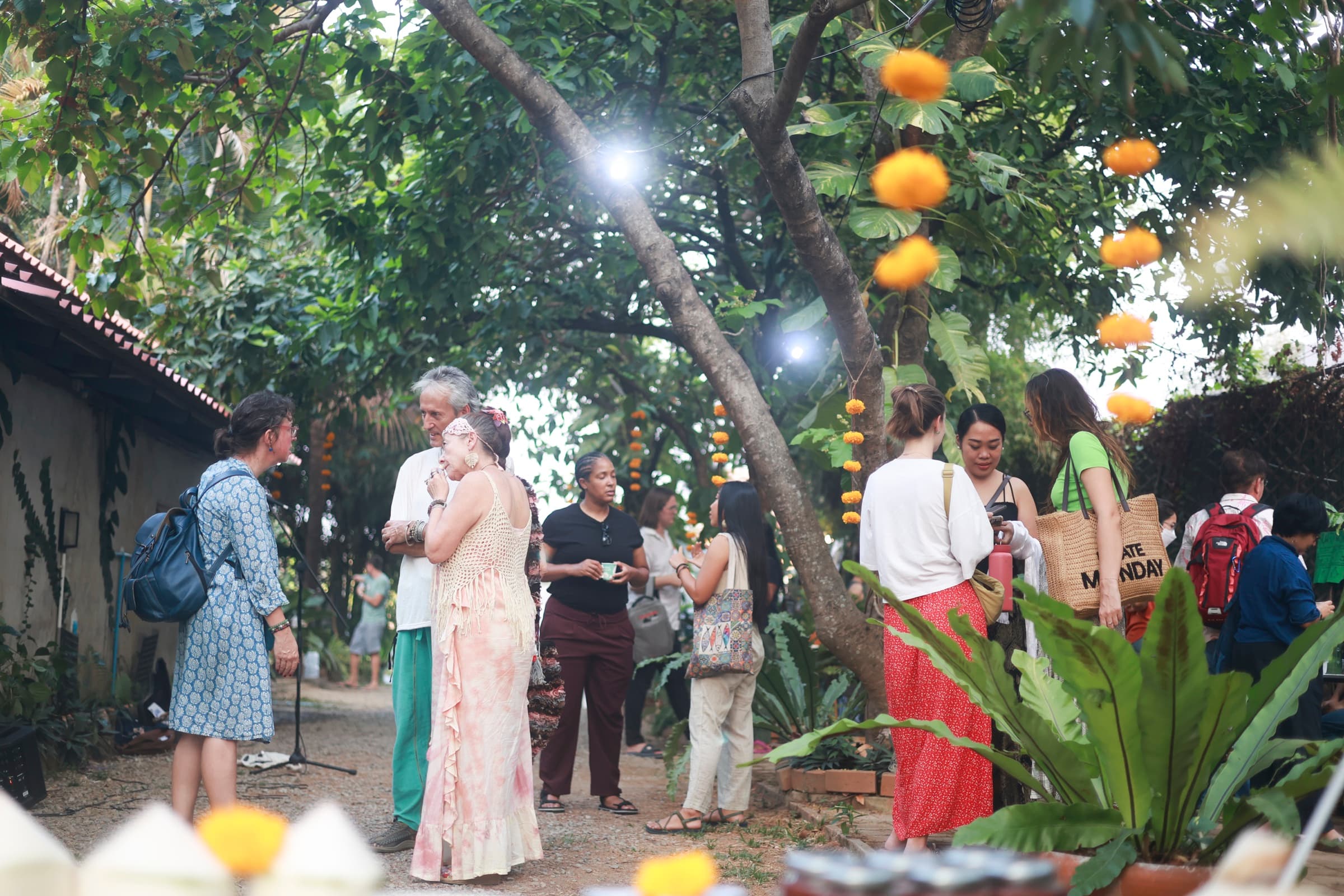 Diverse community gathering in the garden with hanging oranges and string lights