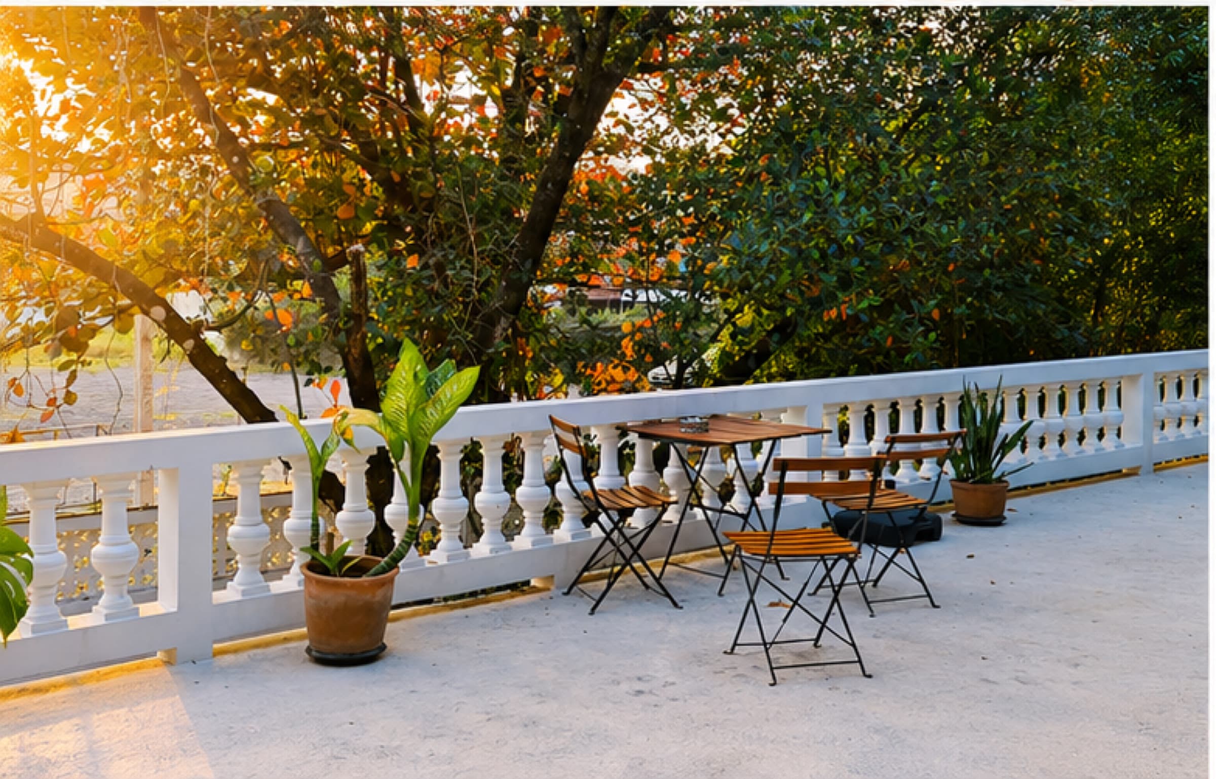 Upstairs terrace at golden hour with bistro table, chairs and tropical garden view