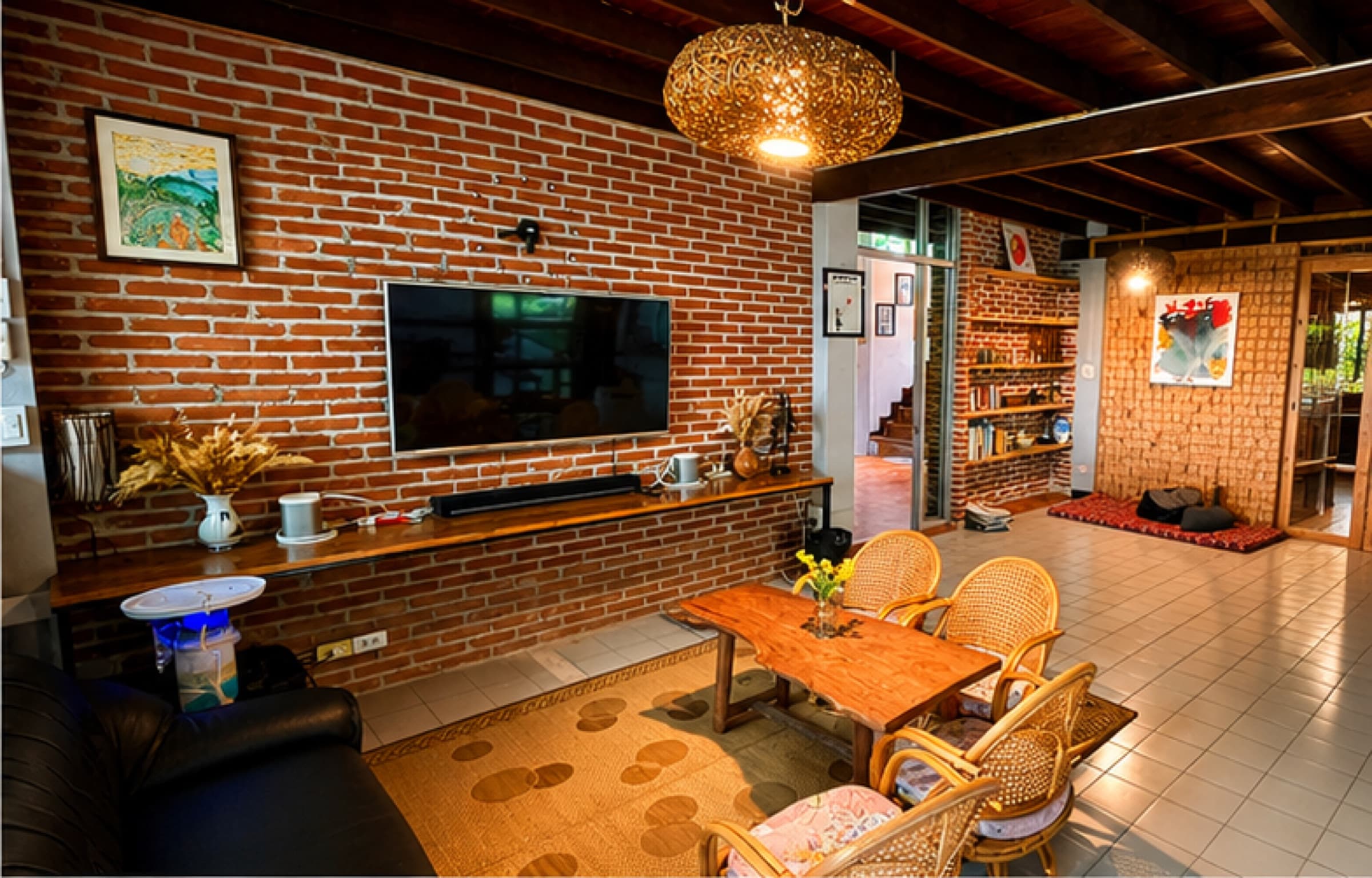 Indoor living and cinema area with brick wall, large TV, framed art and rattan chairs