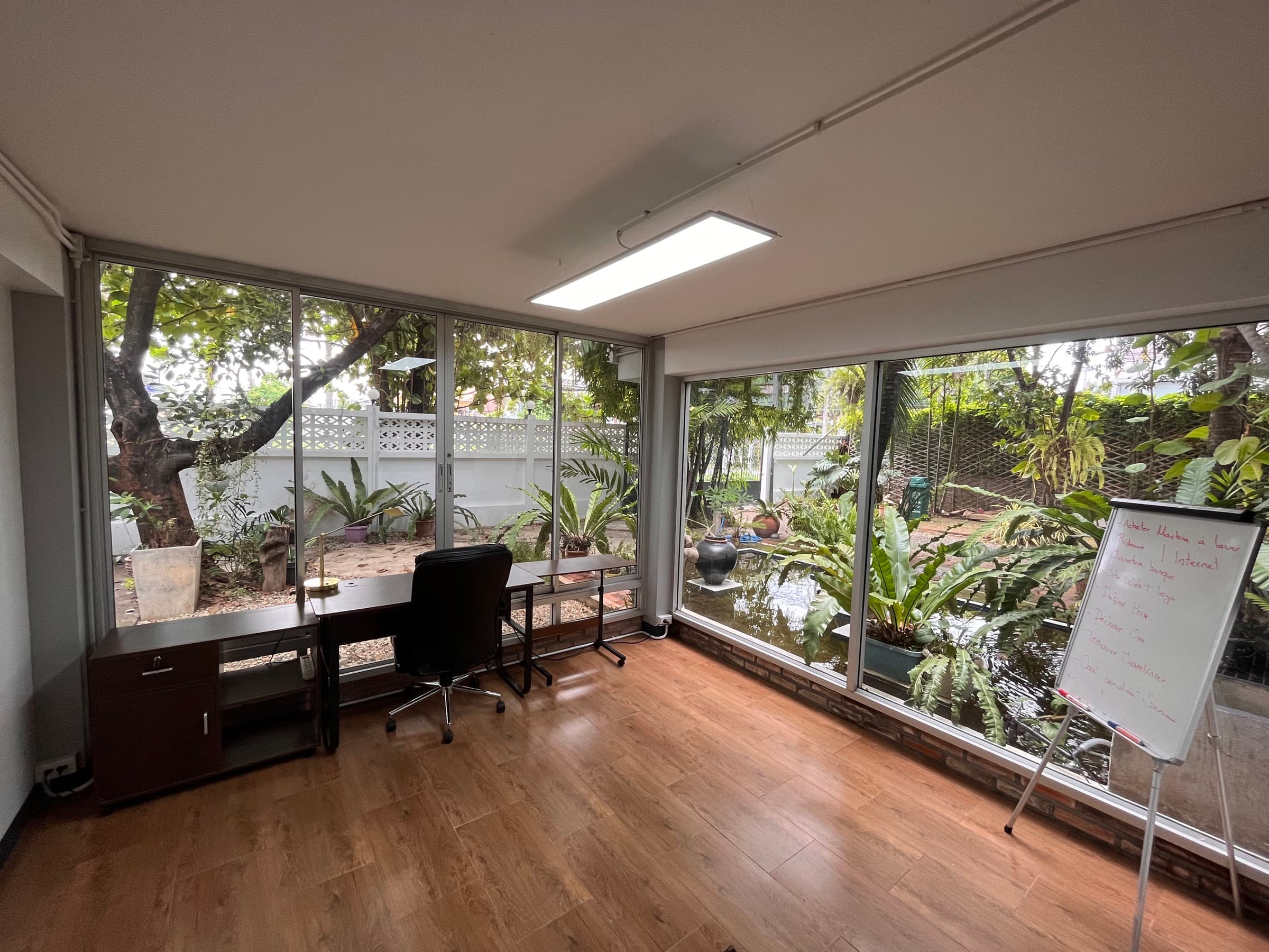 Coworking space with desk, ergonomic chair, and large windows facing the garden